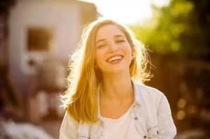 mulher loira sorrindo com fundo ensolarado